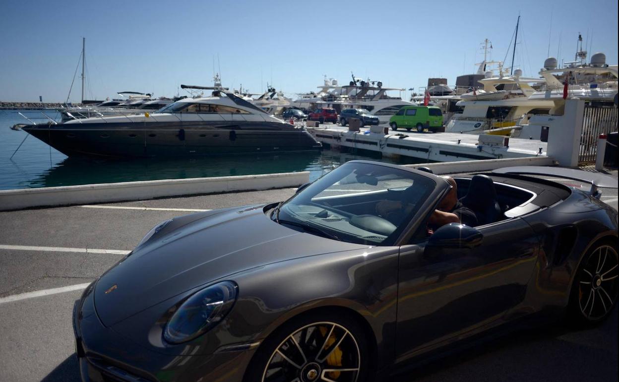 Un hombre conduce un vehículo de alta gama en Puerto Banús, la zona de mayor lujo en Marbella. 