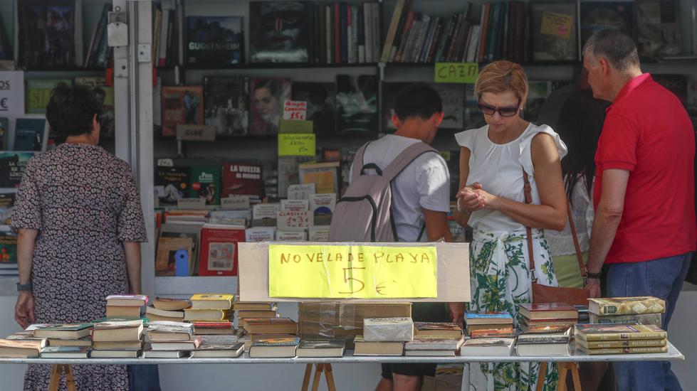 Varias personas se detienen en las casetas de la Feria del Libro Viejo, en la Plaza Alfonso XIII, donde se encuentran todo tipo de ejemplares.