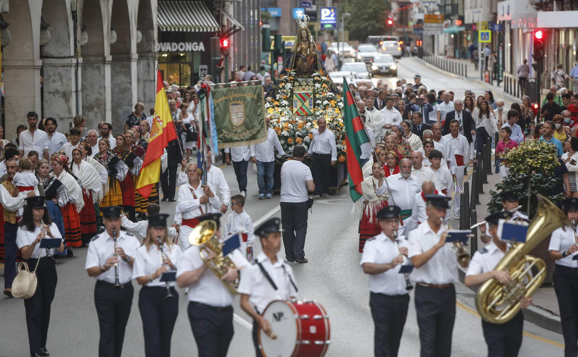 La imagen de la Virgen enfila la calle José María Pereda escoltada por grupos de danzas y la banda de música de la ciudad.