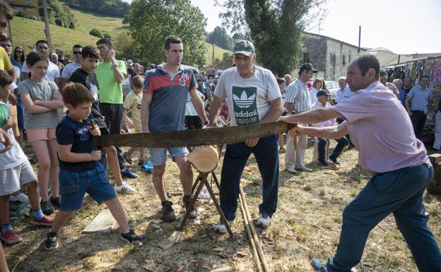 Exhibición de deporte rural por la tarde en Selaya con un niño y un adulto en la corta de troncos. 