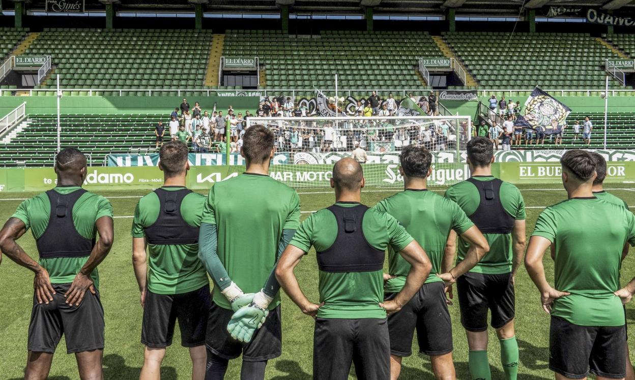 El equipo aguarda en el centro del campo mientras los miembros de la Gradona de los Malditos les mandan un mensaje de ánimo en el entrenamiento de ayer.