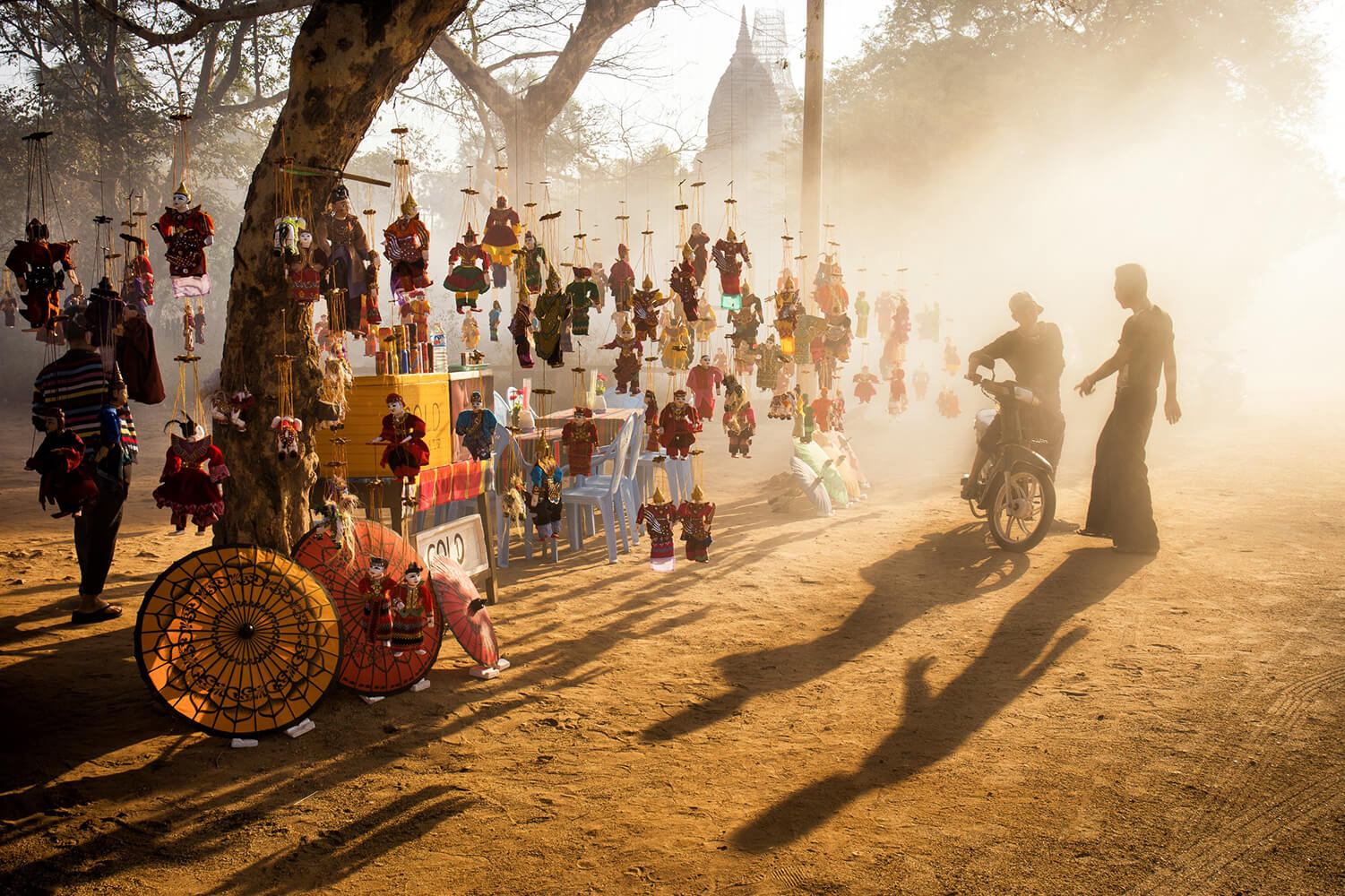 Esta foto disparada hacia la niebla y la luz dorada de la mañana, crea una escena que, mientras captura un aspecto turístico de Myanmar en este puesto de marionetas, también se siente auténtica y encantadora.