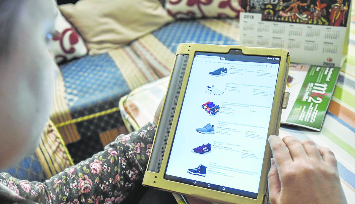 Una señora mira en su tablet calzado deportivo antes de comprarlo