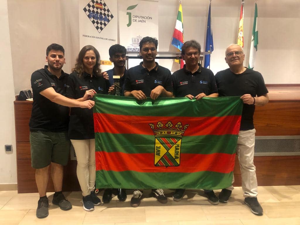 De izquierda a derecha, Enrique Tejedor, Anna Muzychuck, Dommaraju Gukesh, Pentala Harikrishna, Juan Carlos Fernández y Elizbar Ubilava posan con la bandera de Torrelavega en Linares.