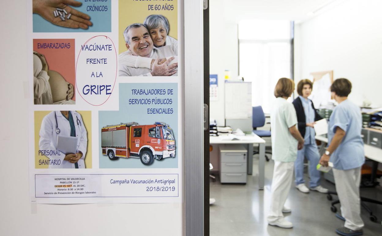 Personal sanitario en un centro de salud con un cartel de la campaña de vacunación de la gripe.