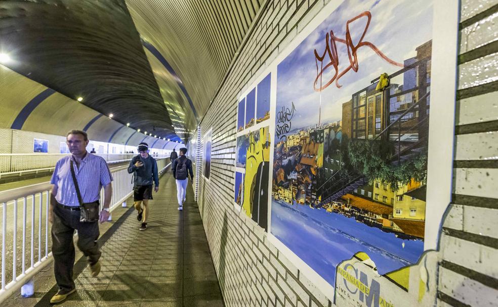 Varios viandantes recorren el Pasaje de Peña junto a las fotografías dañadas. 