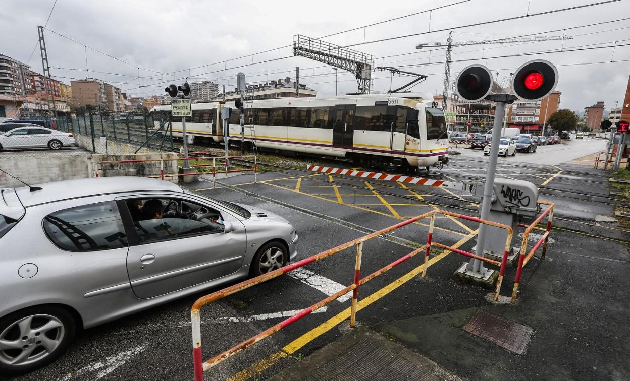 Un tren circula por el paso a nivel de la calle Pablo Garnica, cerca de la estación de tren de Torrelavega. 