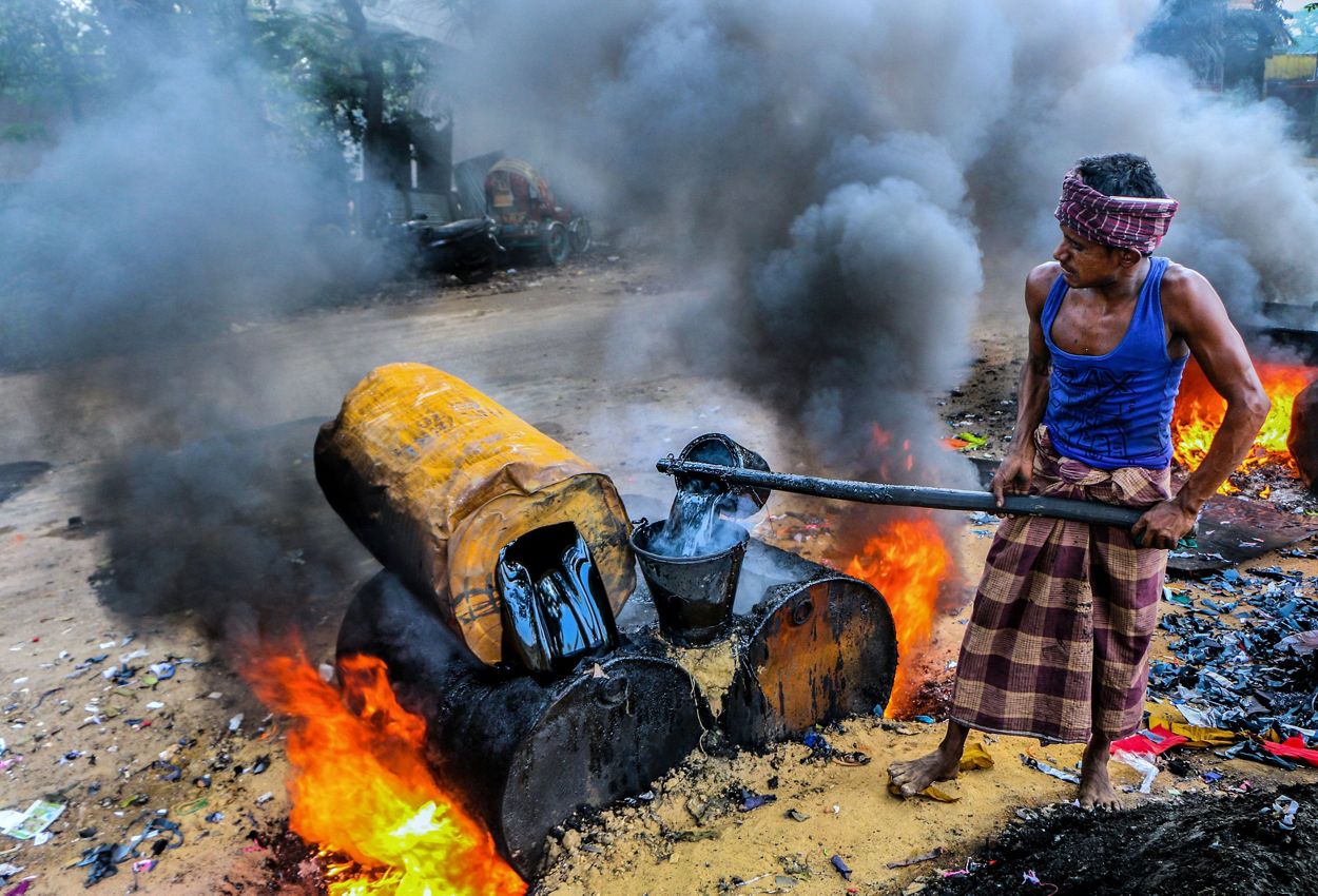 Los trabajadores de la construcción de carreteras de Bangladesh que trabajan en una obra de construcción sufren graves daños por el humo negro y el polvo 