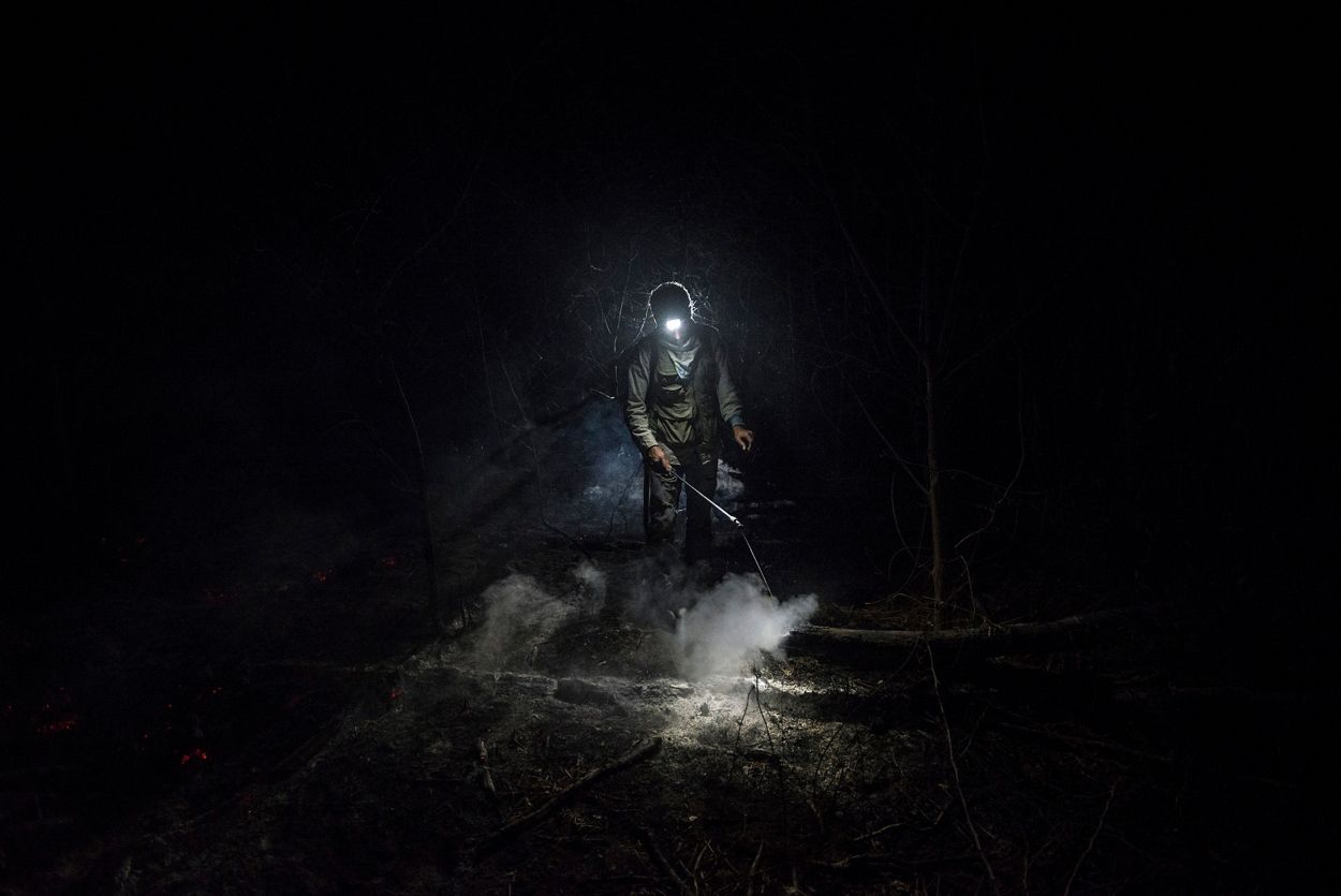 El bombero forestal voluntario Daniel Vargas Osinaga (21) camina a través de un espeso humo en Santa Rosa de Tucabaca, Bolivia. 