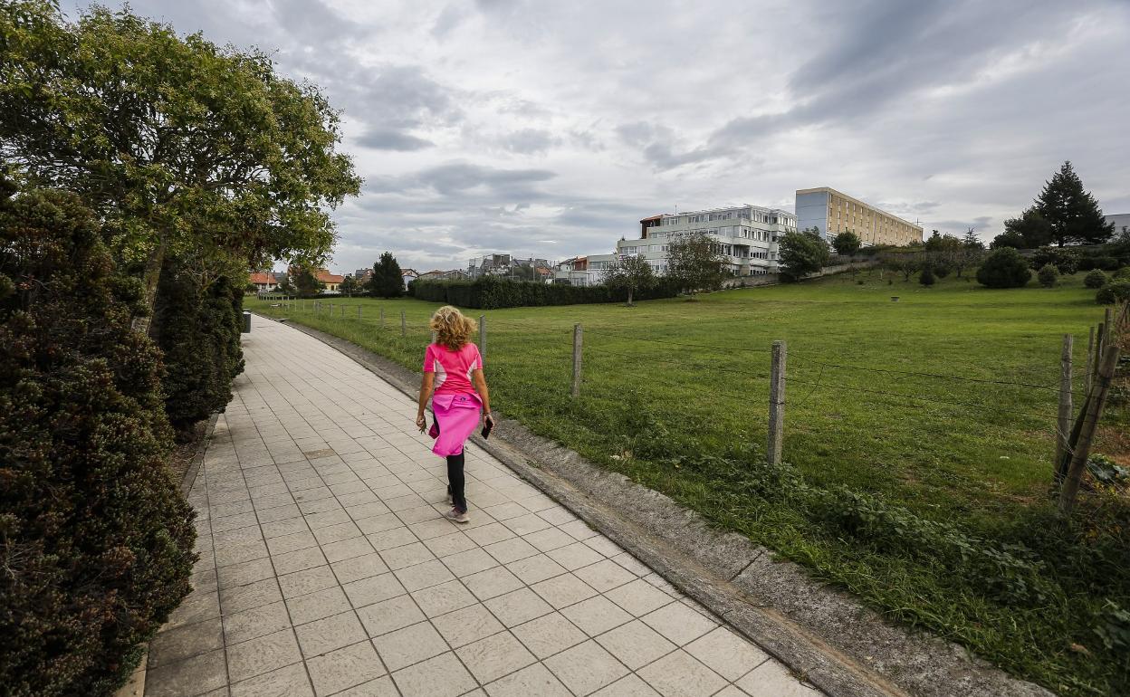 Una vecina camina junto a los terrenos de El Valle donde se construirá el Conservatorio, esta semana, en Torrelavega.