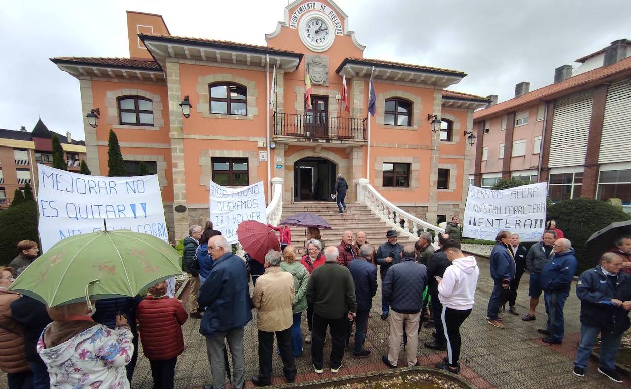 Varias decenas de vecinos se manifestaron hoy frente al Ayuntamiento de Piélagos por las obras que está llevando a cabo el Consistorio en la carretera de Vioño. 