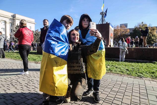 Una mujer y dos niños envueltos en banderas ucranianas posan para una fotografía selfi en la recién reconquistada ciudad de Jersón el 14 de noviembre de 2022.