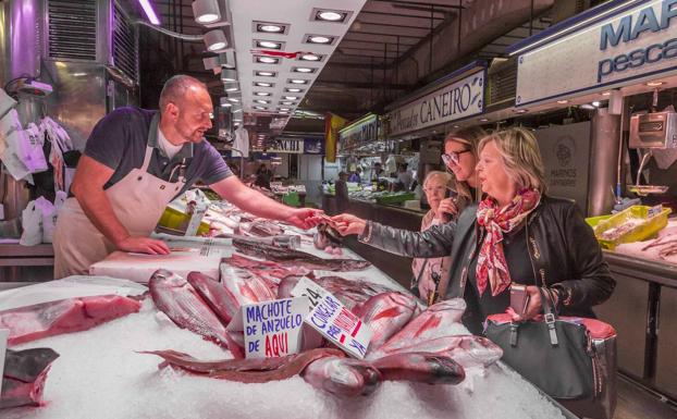 Isaac Fernández, de la pescadería El nieto de Arsenia, en el Mercado de la Esperanza de Santander, ayer, atiende a una clienta. 