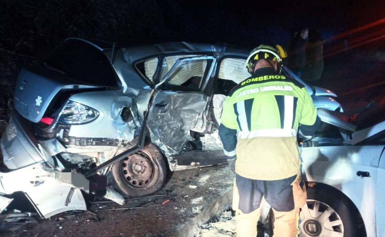 Un bombero revisa uno de los coches con el otro turismo implicado totalemente destrozado.