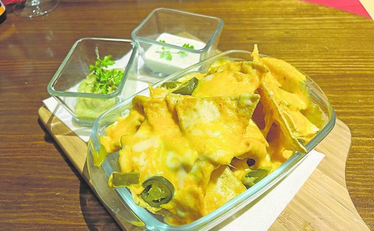 Nachos con cheddar fundido, jalapeños, dips de queso y guacamole. 