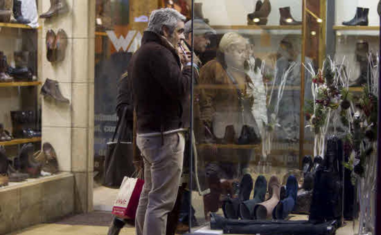 Varias personas miran el escaparate de un comercio de Santander durante el periodo de rebajas de invierno en una imagen de archivo.