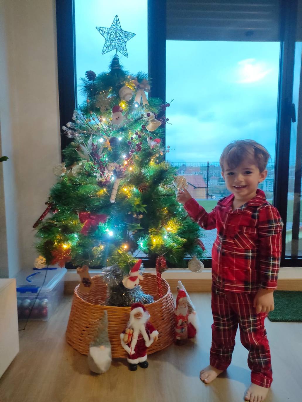 Óliver Fernández, de Santander, tiene solo dos añitos pero vive intensamente estas fechas y adora a Papá Noel. Es la primera vez que colabora en la colocación del árbol, situado frente a la terraza de su casa.