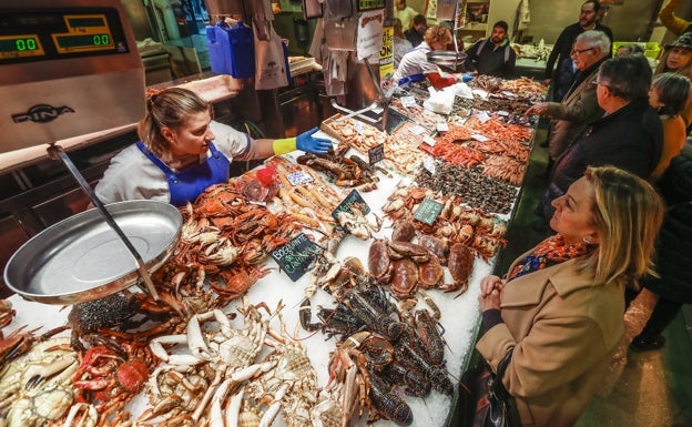 Una trabajadora de Mariscos Ana, puesto ubicado en el Mercado de la Esperanza de Santander, atiende a una clienta.