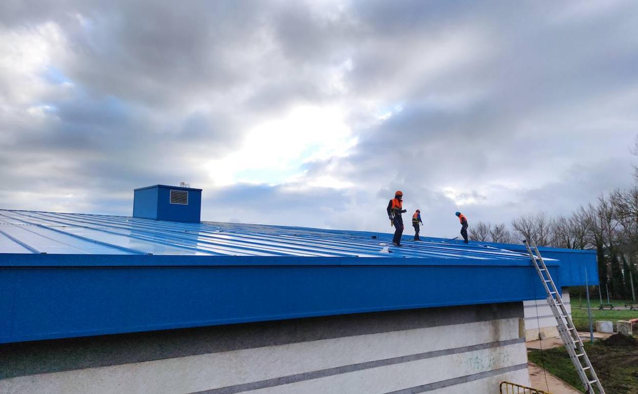 Obreros realizando los trabajos para reparar la cubierta de la piscina. 