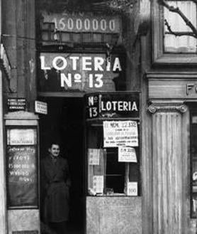 Imagen secundaria 2 - La administración número 13 de Loterías sigue hoy prácticamente igual que cuando se inauguró. Los rótulos, los cristales y los marcos son los originales, aunque el cartel más grande está actualmente cubierto con el oficial de Loterías del Estado. En la foto de arriba, Olga Gutiérrez, quien gestiona ahora el negocio con su socia Teresa Gajano.