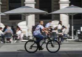 Un hombre hace uso de su bicicleta por la plaza Porticada de Santander.