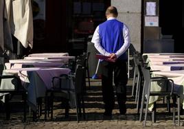 Un camarero repasa las mesas de la terraza de su establecimiento