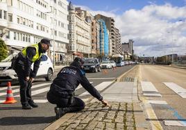 Dos agentes de la Policía Local de Santander realizan mediciones en el lugar del accidente