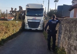 Un policía local da indicaciones al camionero para que salga de la zona donde ha quedado atrapado