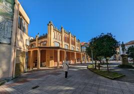 Una laredana camina junto a la fachada lateral del Mercado de Abastos de Laredo, que tiene previsto abrir un nuevo acceso para comunicar con la calle Escultor José Grajera