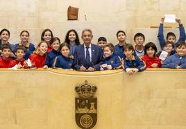 Miguel Ángel Revilla, en la tribuna de oradores del Parlamento, rodeado por los alumnos de sexto de Primaria de los Escolapios