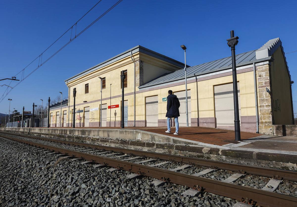 Un vecino aguarda la llegada del tren, ayer, en la estación de Sierrapando, frente al edificio abandonado que sigue pendiente del plan