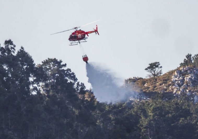 El helicóptero del 112, esta mañana, haciendo descargas de agua en la zona norte de Peña Cabarga para apagar los fuegos activos.