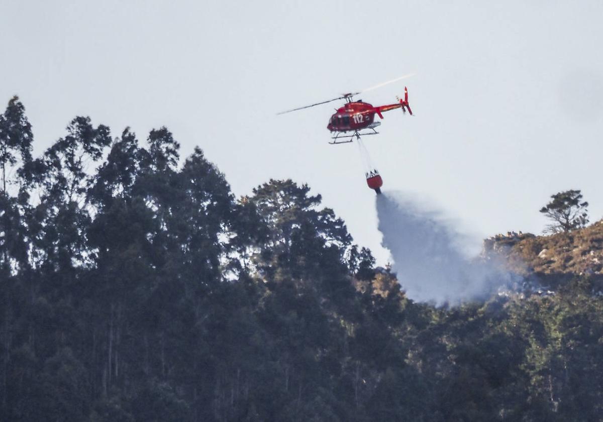 Un helicóptero del 112 extinguiendo uno de los incendios esta mañana en Peña Cabarga