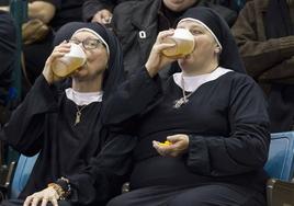 Dos mujeres disfrazadas de monjas beben cerveza en una grada