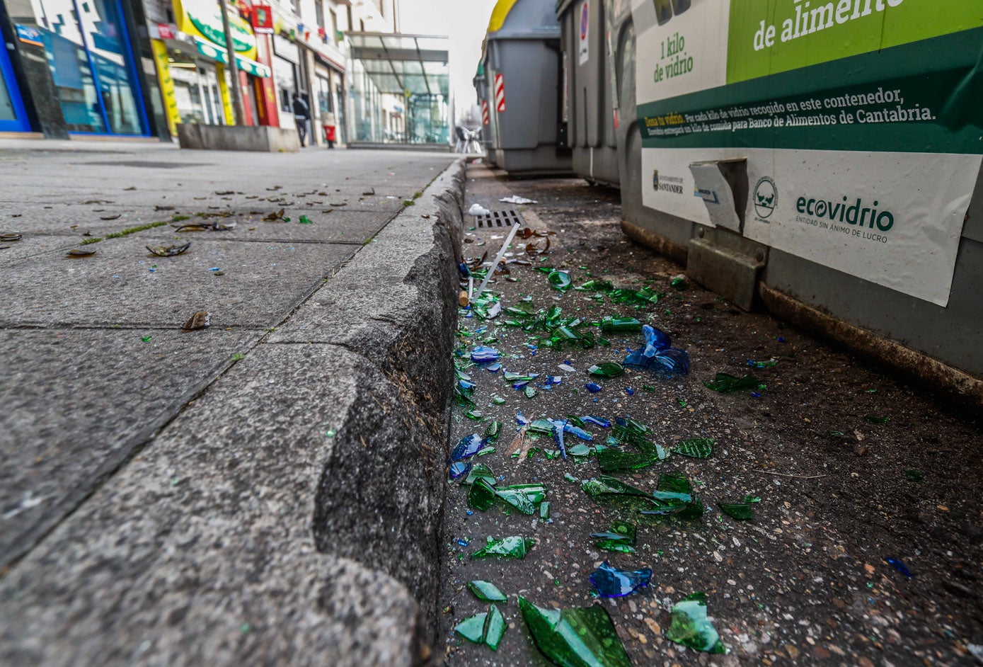 Restos de vidrio en el suelo junto a uno de los contenedores repartidos por Santander para tirarlos. Los pliegos del nuevo convenio incluyen un aumento de los ratios de limpieza que se reforzará en periodos como verano, Semana Santa y Navidad. 