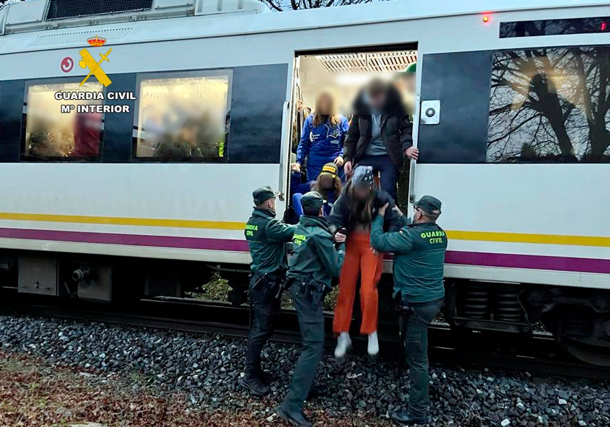 Los agentes de la Guardia Civil evacuan a uno de los pasajeros del tren de FEVE.