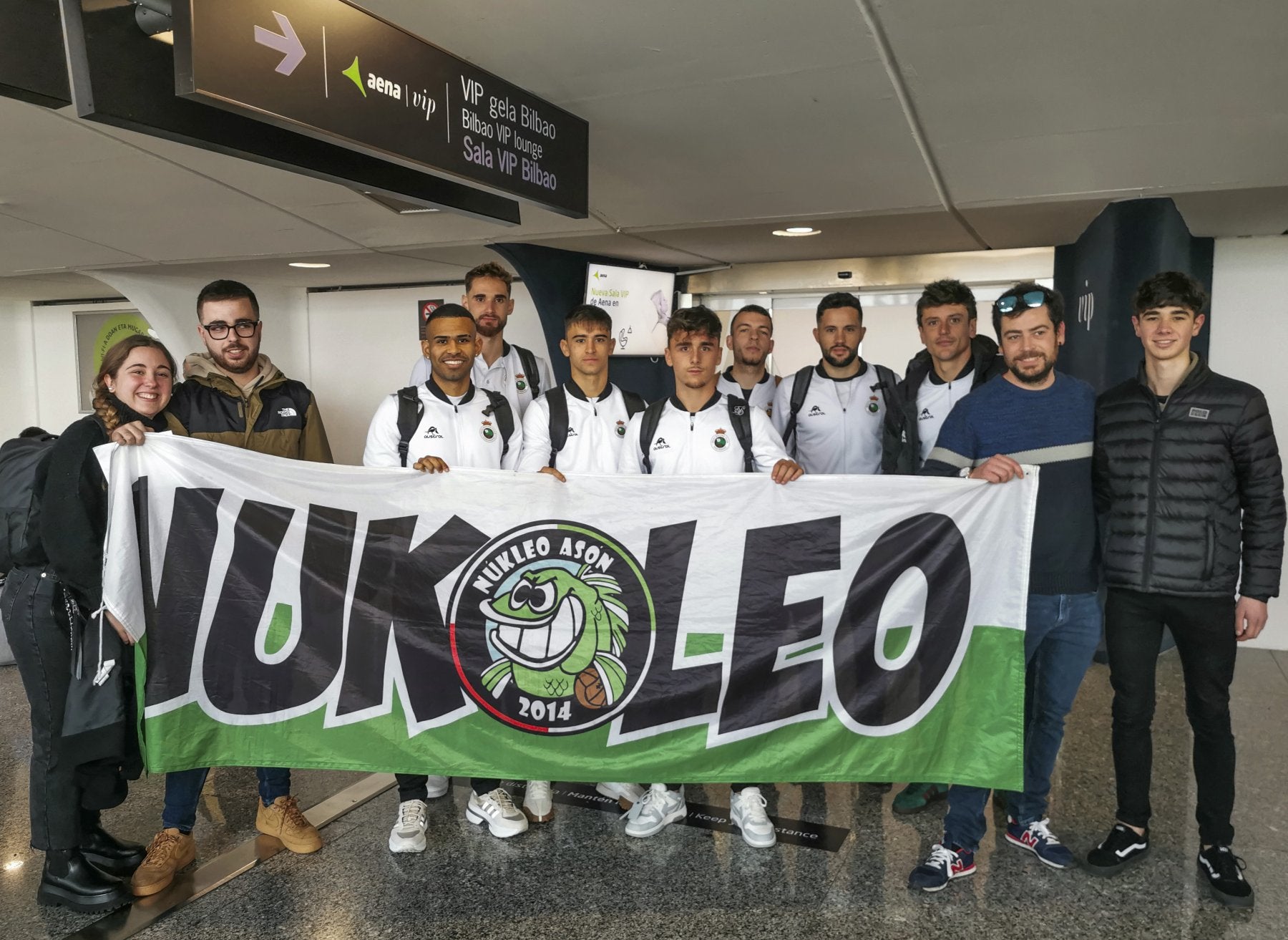 Varios jugadores de la plantilla racinguista junto a aficionados de Nukleo Asón en el aeropuerto de Loiu, antes de viajar a Málaga.