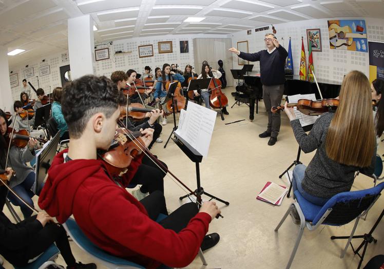 David Cubillas dirige a los músicos de la orquesta, en el salón de actos.