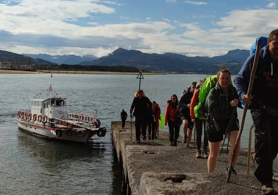 Peregrinos desembarcan en el Pasaje de Santoña cuya plataforma exhibe un aspecto deteriorado por las décadas de uso sin renovación.