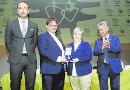 Aurelio Cayón, representante del colegio La Paz, y Nuria Arias, de los Sagrados Corazones, sostienen la Medalla de Oro, flanqueados por López Estrada y Revilla, este miércoles, en el Teatro Concha Espina.