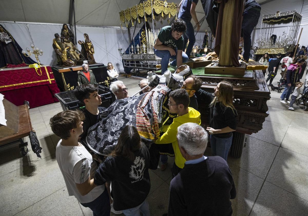 Hermanos de la Cofradía de los Dolores bajan a la Virgen para instalarla sobre el paso de palio, en la Porticada, con el que saldrá en procesión en Semana Santa.