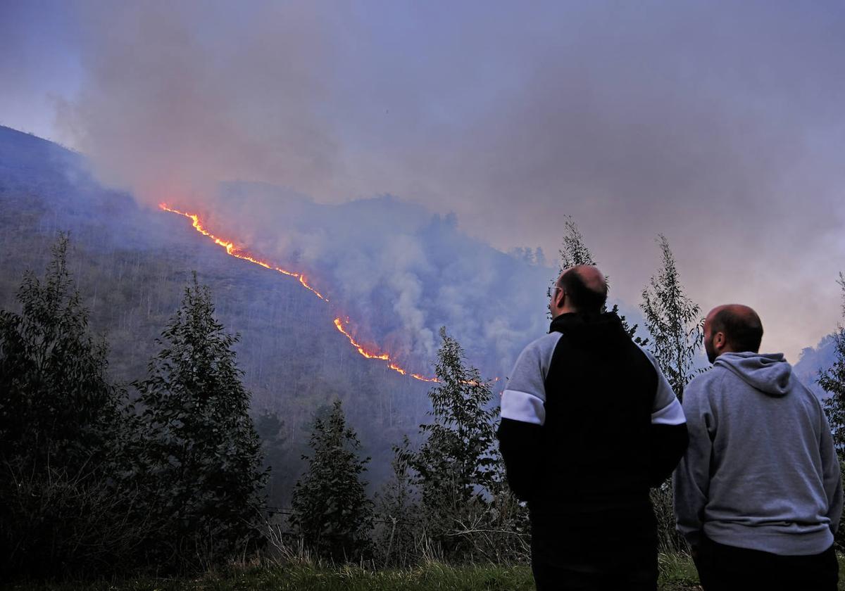 Dos vecinos observan la evolución del incendio en la Hoz de Santa Lucía, en la zona de Cabezón de la Sal.