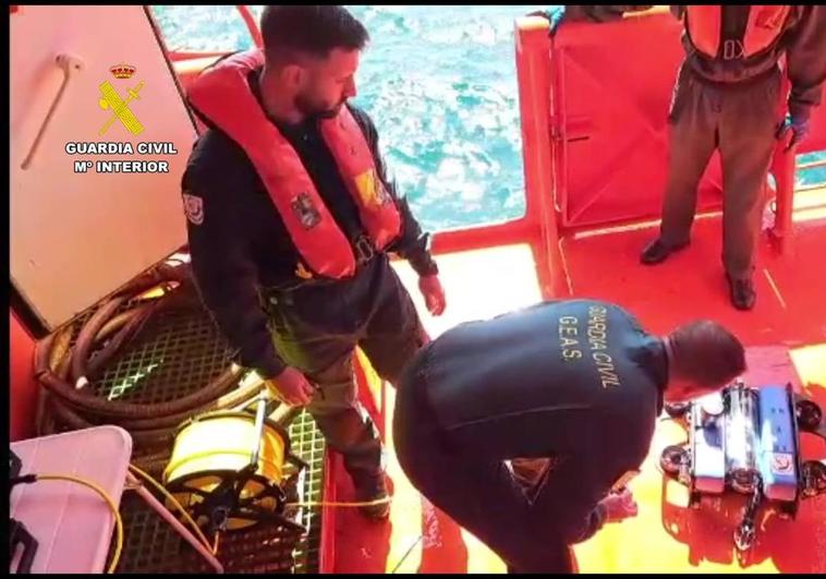 Efectivos de los Grupos Especiales de Actividades Subacuáticas de la Guardia Civil junto al robot submarino que ayuda en la búsqueda del maquinista del Vilaboa Uno.