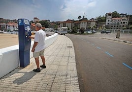 Un hombre abona el precio por aparcar en la zona azul de la playa de Comillas.