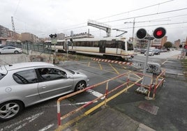 Un coche aguarda en el paso a nivel de Pablo Garnica, mientras un tren sale de Torrelavega en dirección a Santander.