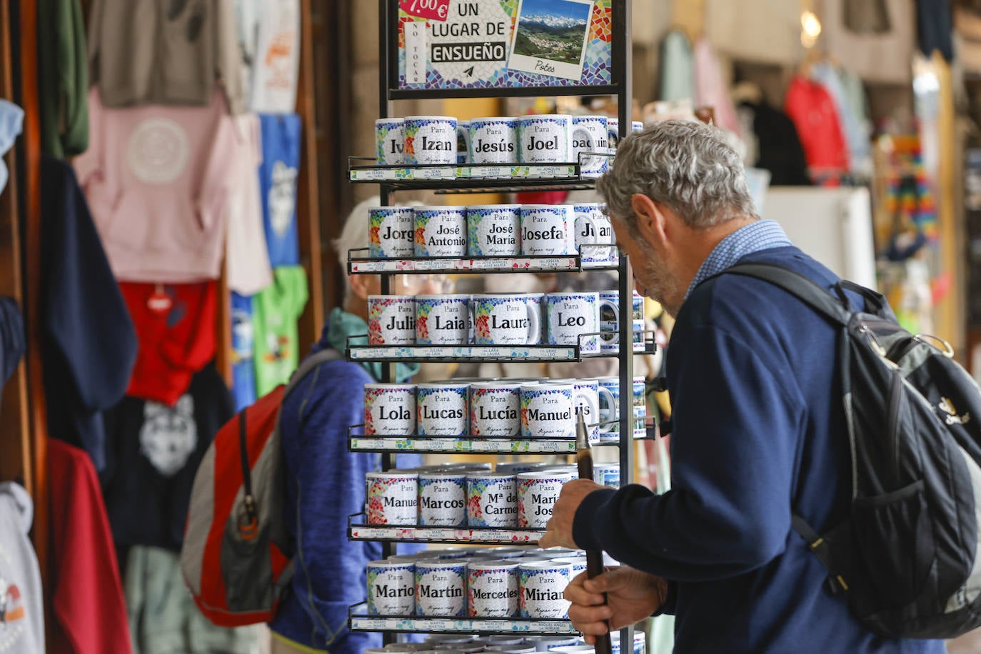 Un peregrino observando las populares tazas de nombres que vende uno de los comercios ubicados en los soportales.