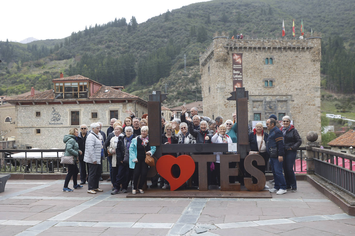 Un grupo de turistas posa con la escultura de Potes.