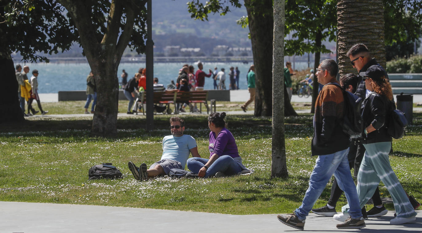 Una pareja descansa en el césped de los Jardines de Pereda.