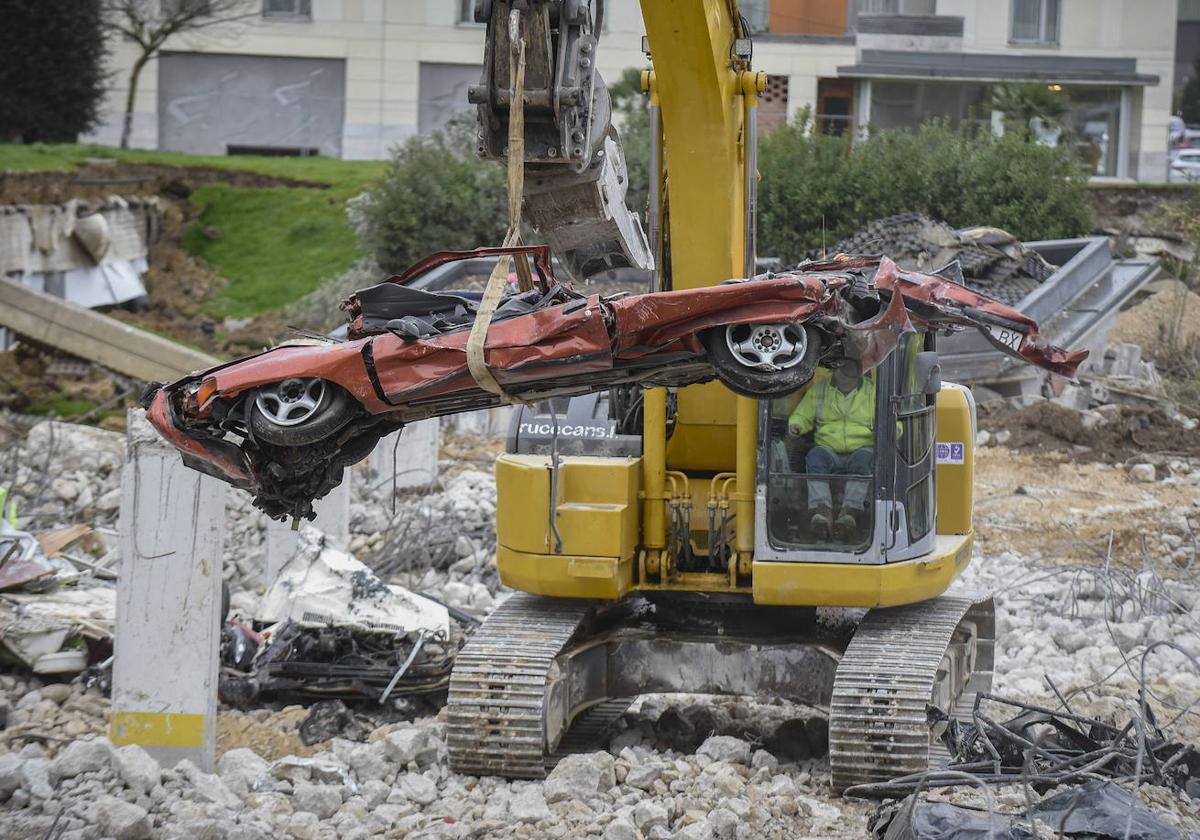 Una máquina excavadora carga con un vehículo aplastado tras el derrumbe de Nueva Montaña.