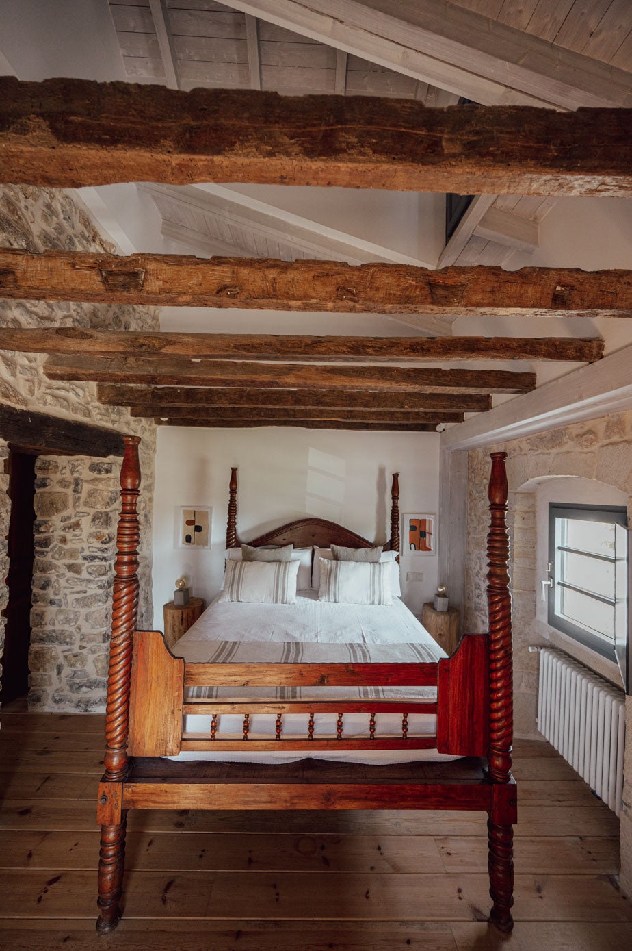 Cama de anticuario, sobre la cual se ve las vigas de madera originales y las blancas, hechas con la reforma.